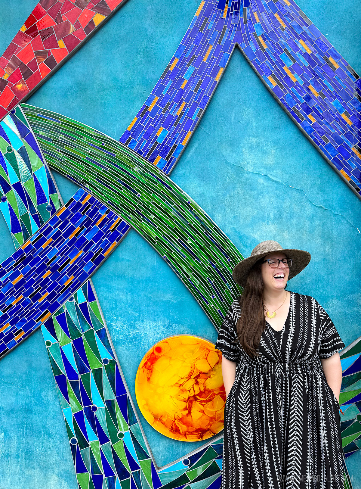 woman laughing in front of a tile mural in downtown Oly historic district