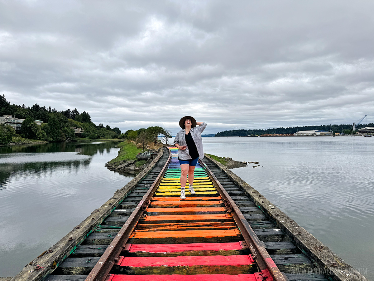 woman laughing while walking along railway painted rainbow colors