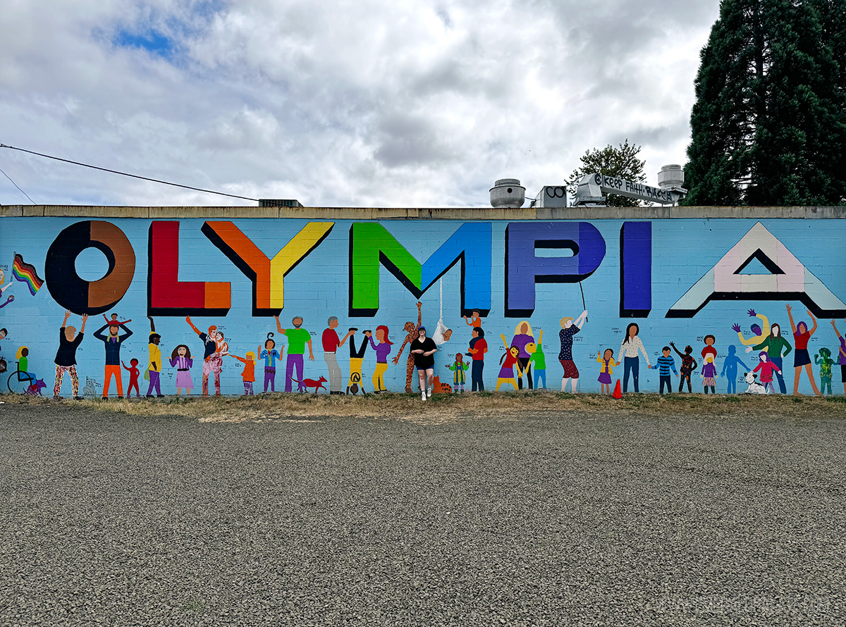 woman standing in front of an Olympia mural