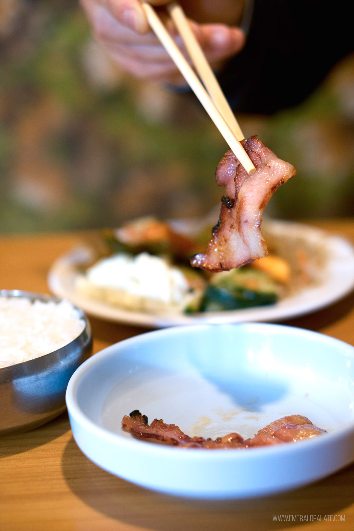 person picking up pork with chopsticks from a Tacoma restaurant