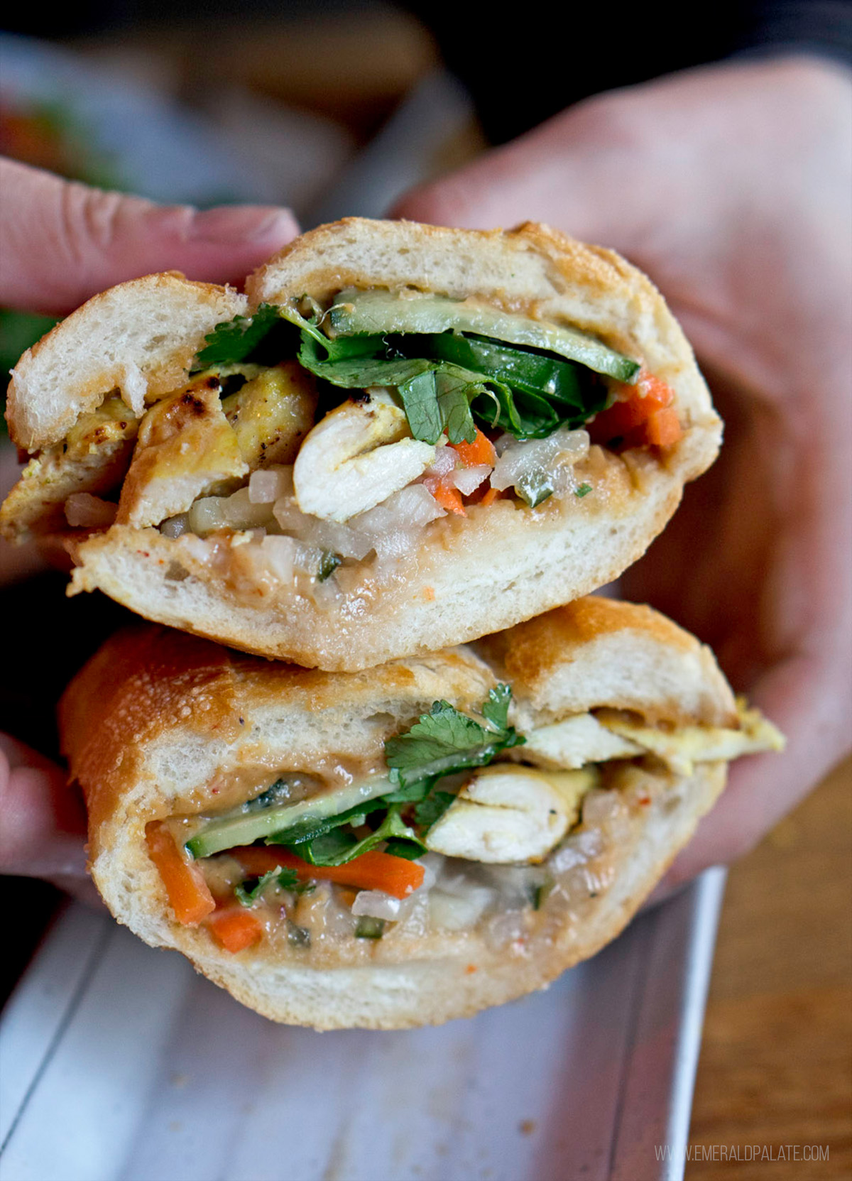 person holding two halves of a chicken banh mi sandwich