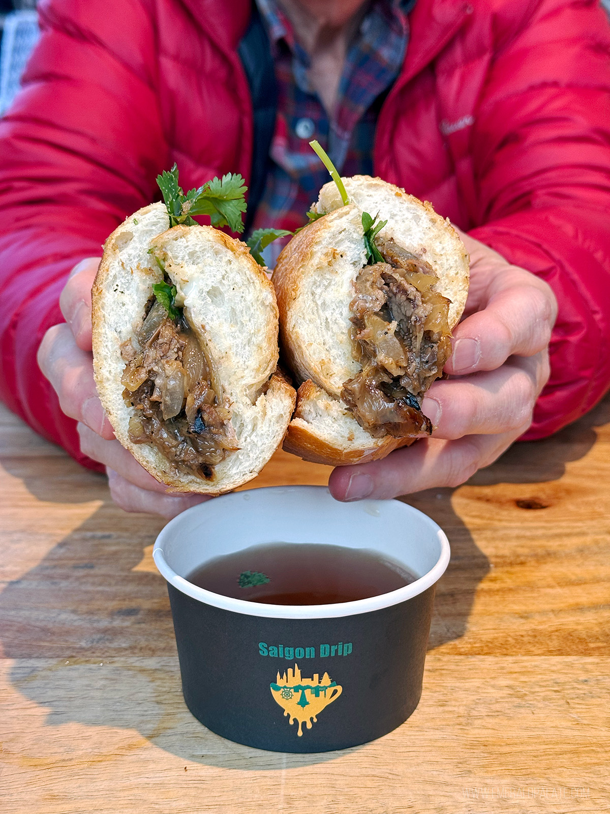 person holding 2 halves of a brisket banh mi, one of the best sandwiches in Seattle