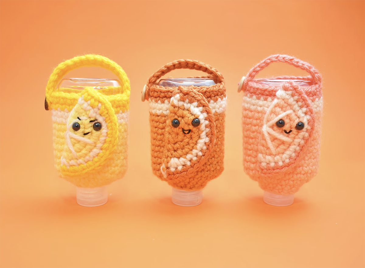 Three crochet hand sanitizer holders designed as a lemon, an orange, and a grapefruit