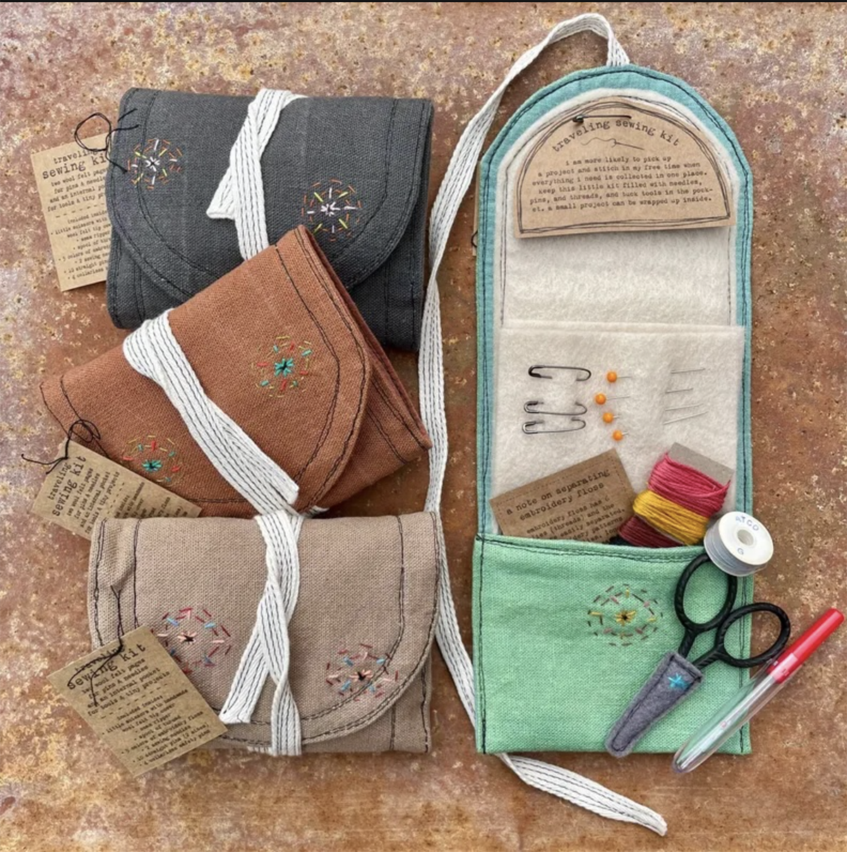 Four travel sewing kits, and one is open to reveal a pair of scissors, thread, and pins