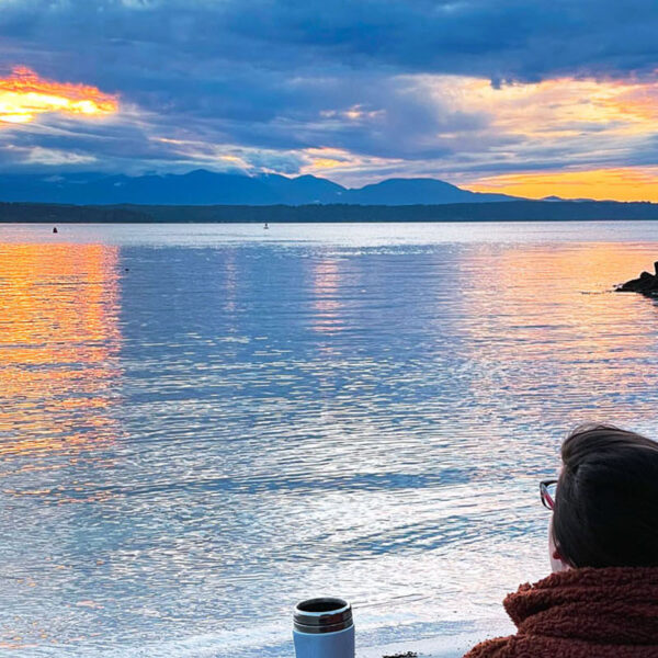 woman enjoying sunset on a beach that's one of the best hidden gems in Seattle