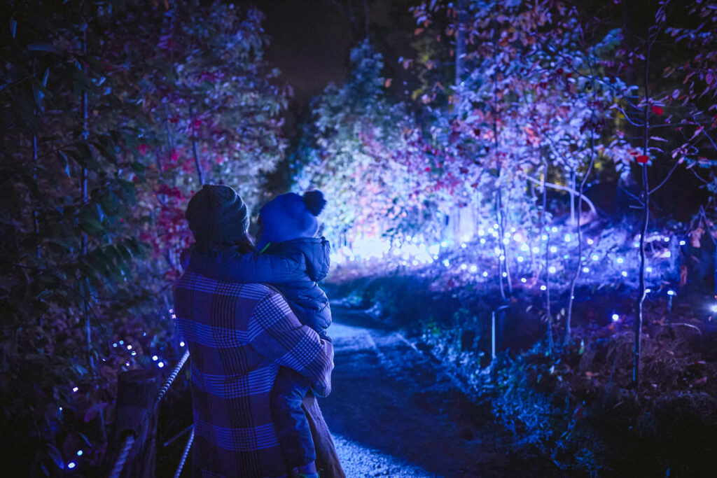 woman holding a child standing in front of a huge light installation