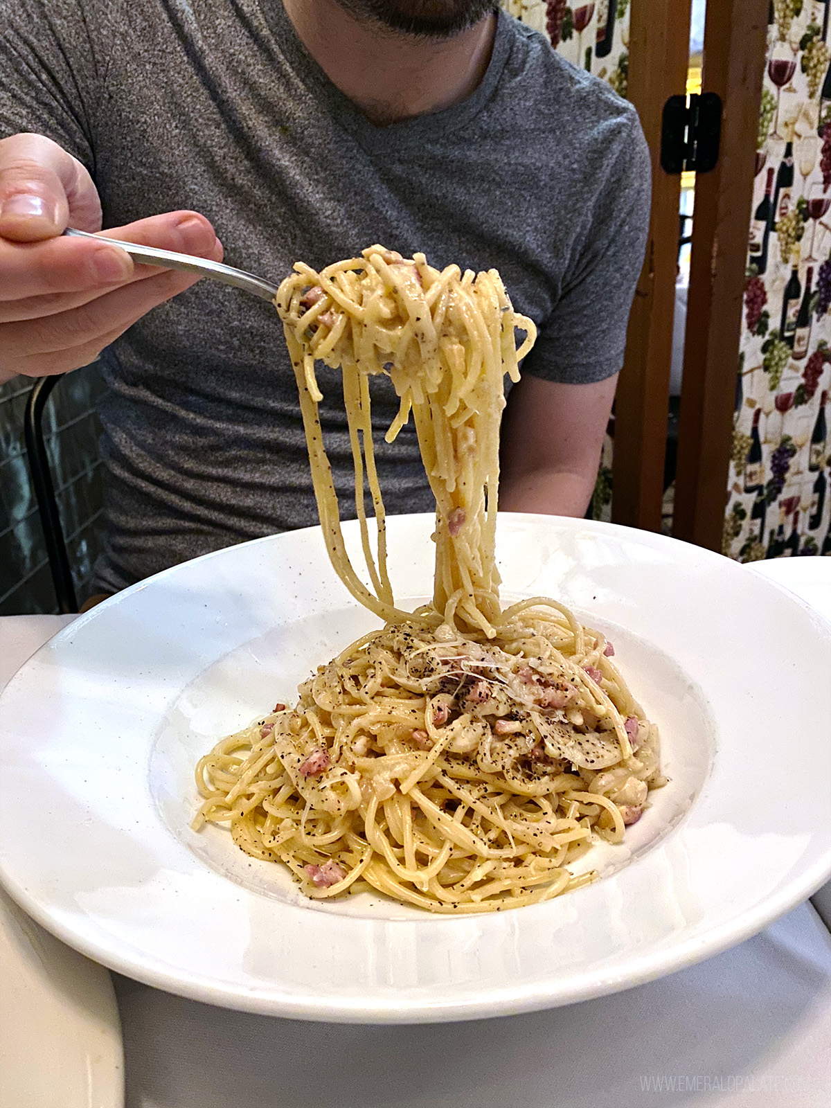 person picking up carbonara noodles from one of the hidden gem restaurants in Seattle