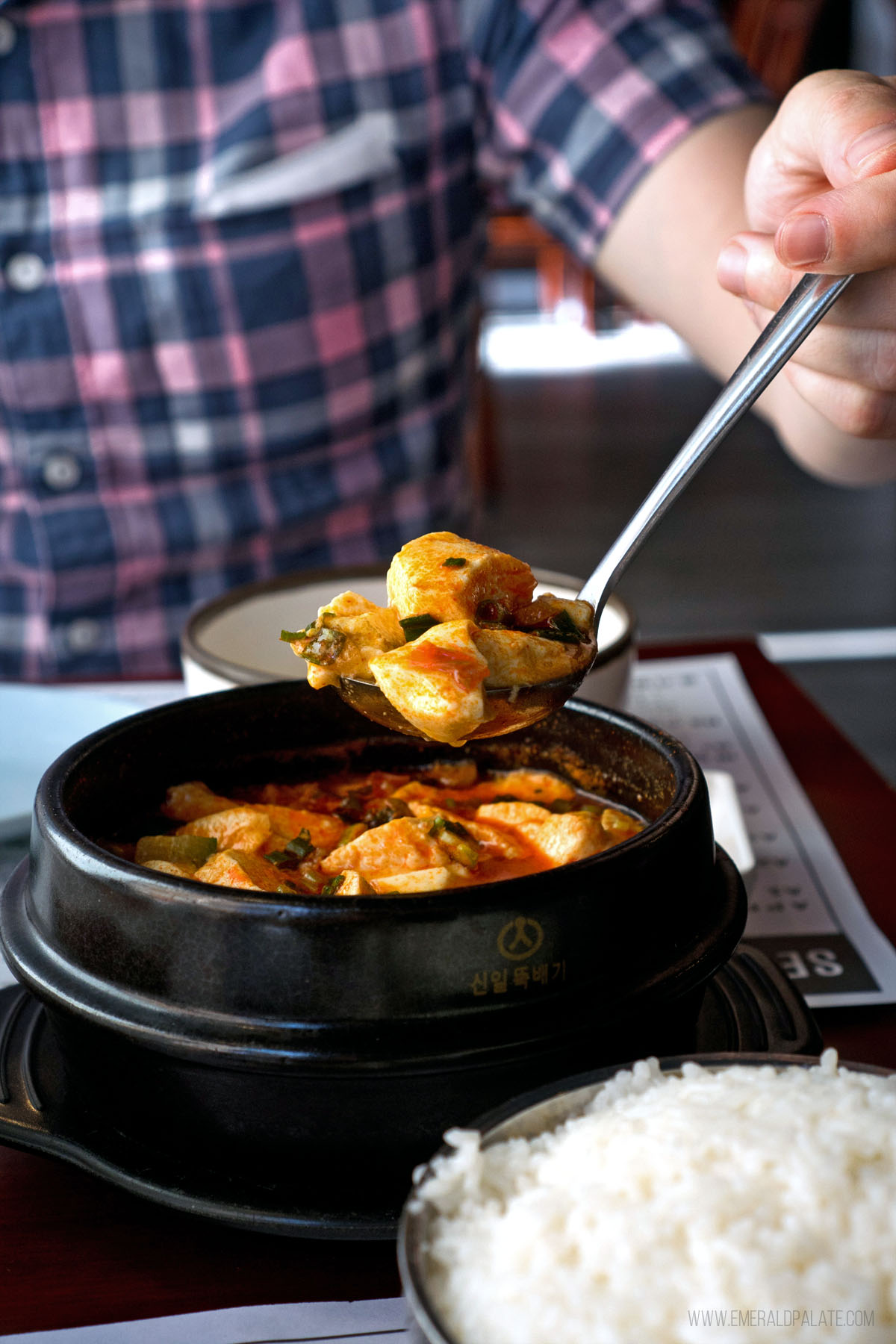 person picking up a spoonful of soondooboo from a Korean restaurant in Seattle