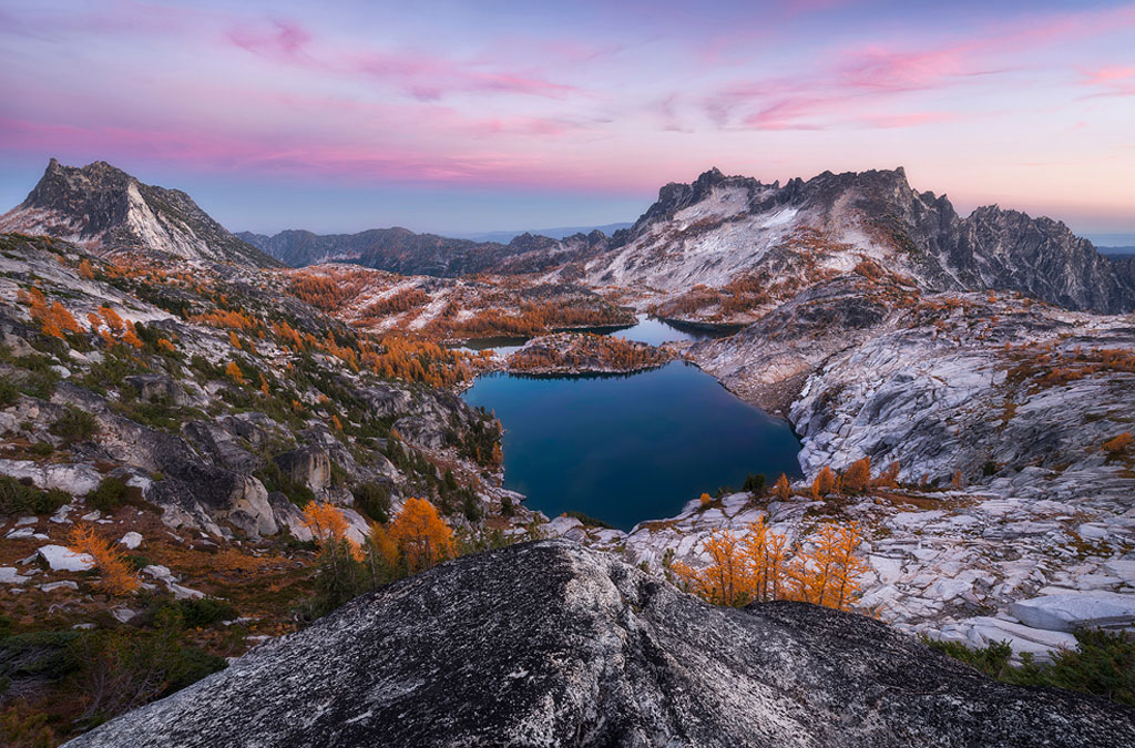 alpine lake surrounded by larches and snow