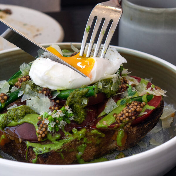 person cutting into an egg on top of toast at one of the hidden gem restaurants in Vancouver BC