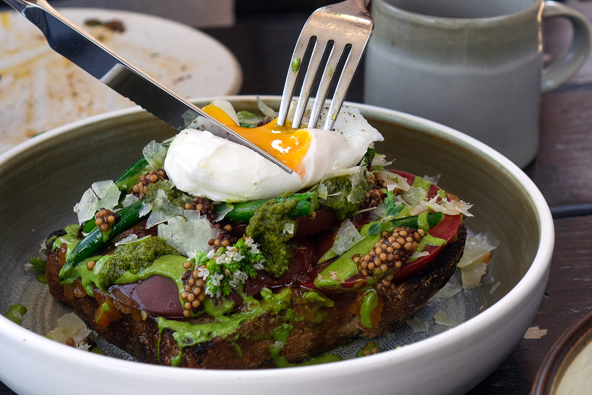 person cutting into an egg on top of toast at  one of the hidden gem restaurants in Vancouver BC