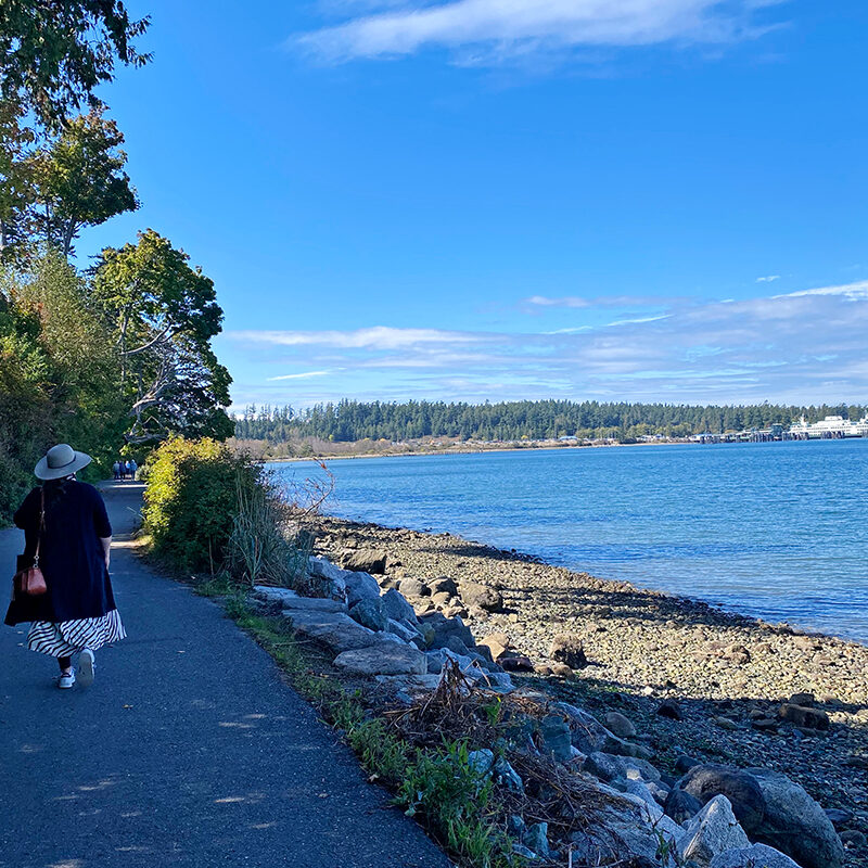 woman walking along a trail looking out onto the ferry during a road trip in Washington state