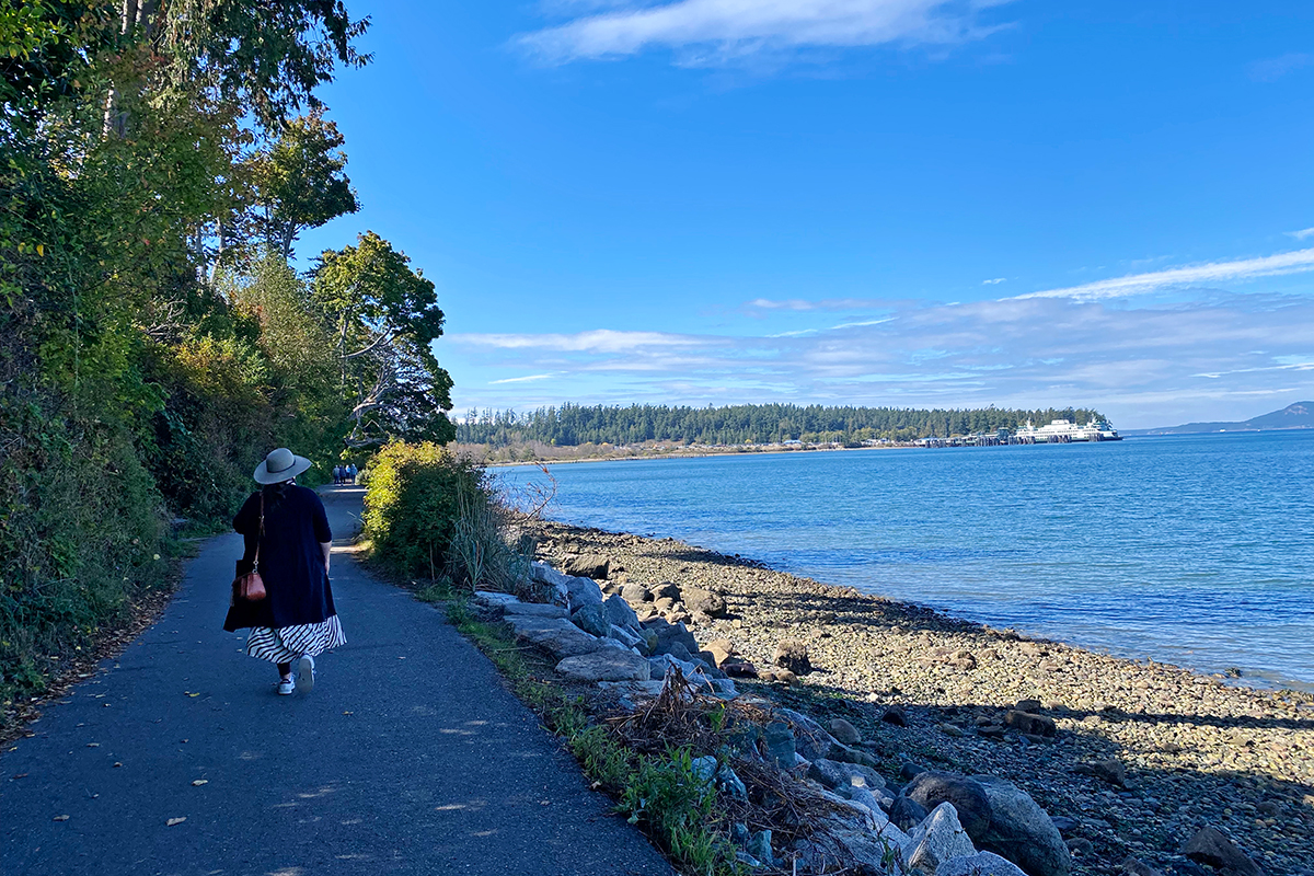 woman walking along a trail looking out onto the ferry during a road trip in Washington state