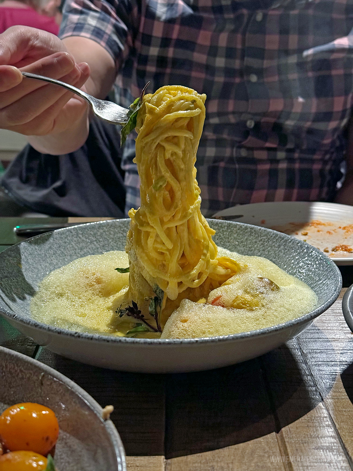 person pulling noodles with a fork from a place to eat in LA