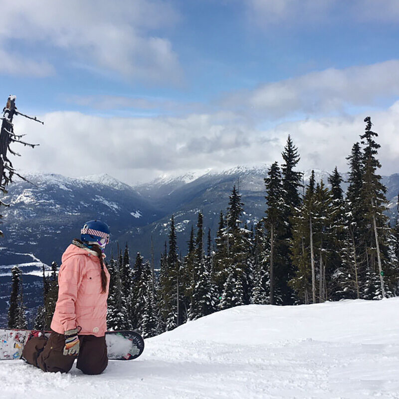 woman taking a break while snowboarding to take in views, one of the best activities in Whistler in winter