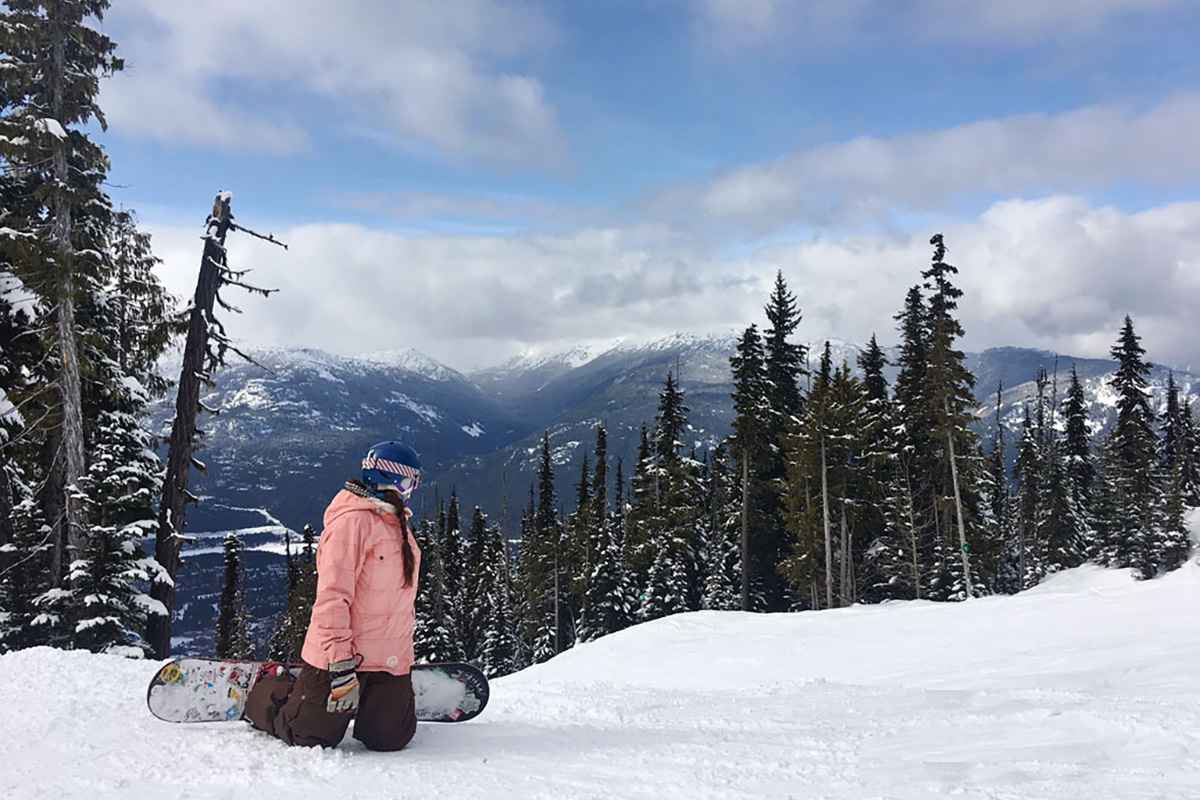 woman taking a break while snowboarding to take in views, one of the best activities in Whistler in winter