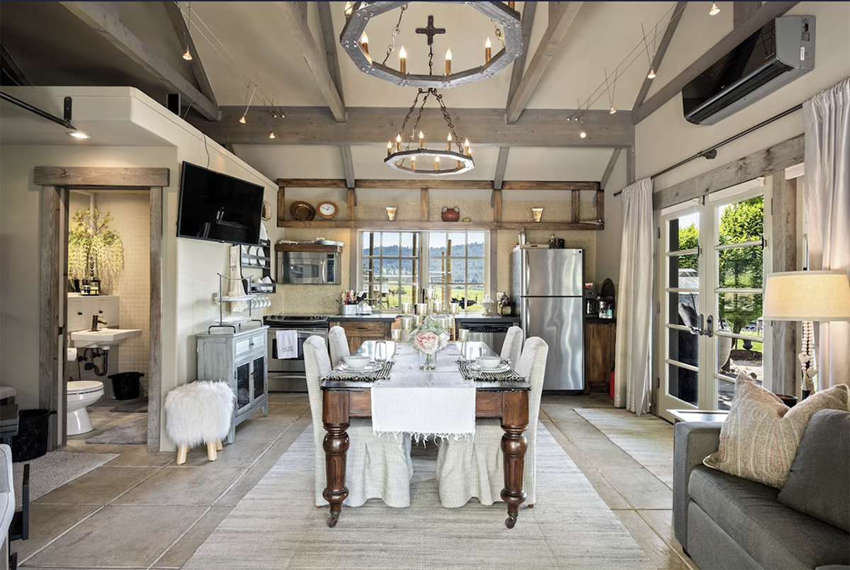 French cottage-style home with vaulted ceilings, beams, and ornate chandelier