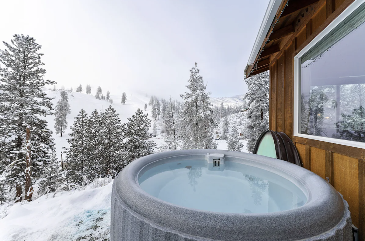 hot tub outside a cabin loverlooking a snowy landscape