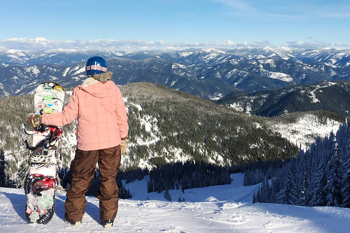 woman looking at mountains in the distance while snowboarding at one of the best ski resorts in Washington