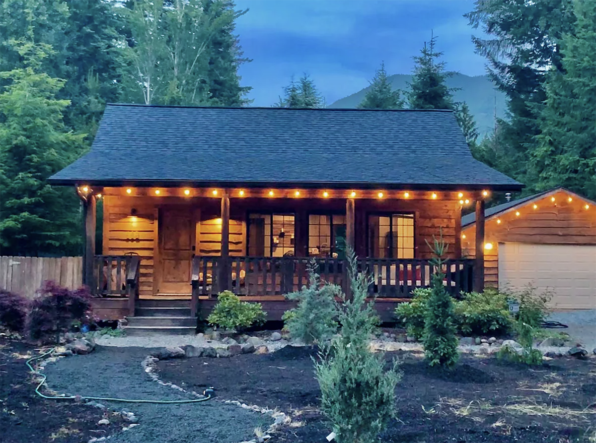 exterior of a log cabin at night with string lights