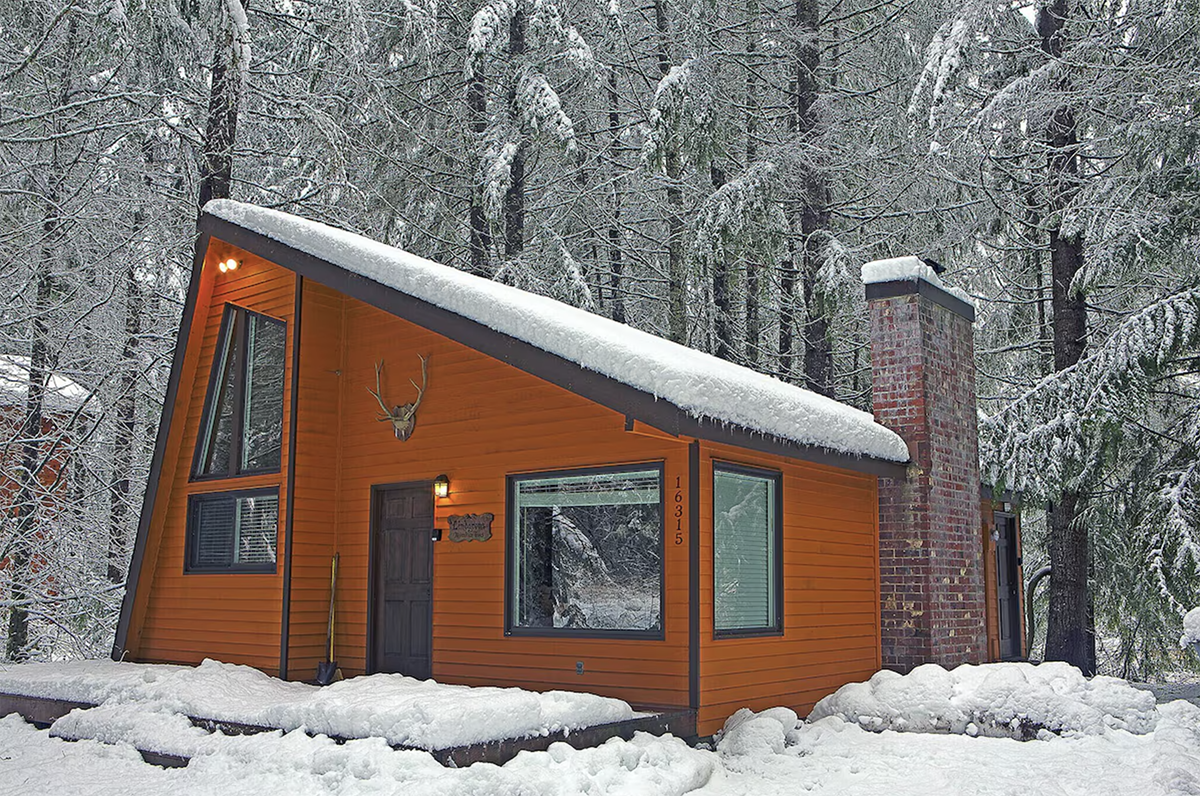 exterior of an a-frame cabin covered in snow