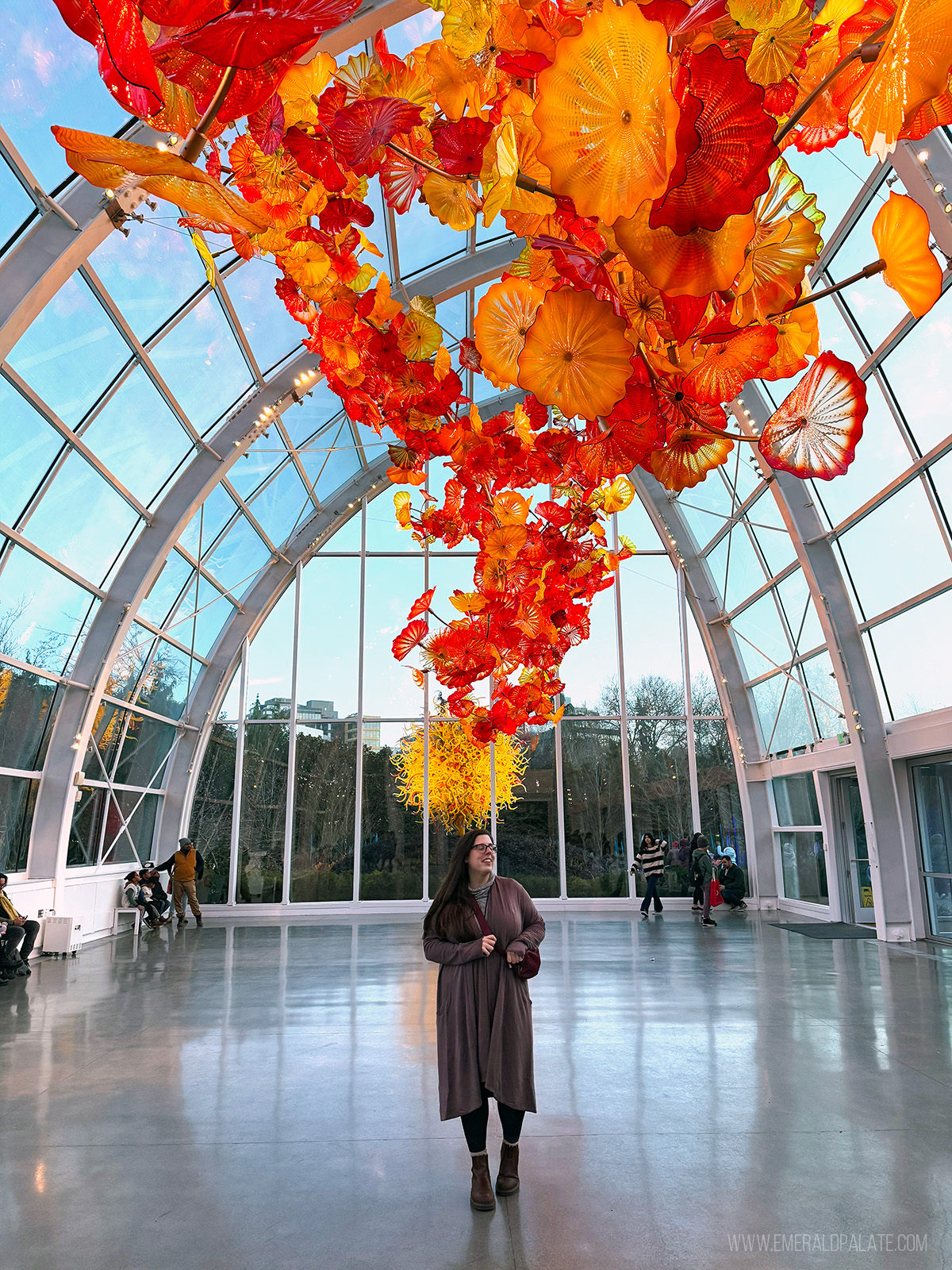 woman walking under a huge glass blown art sculpture at a Seattle museum