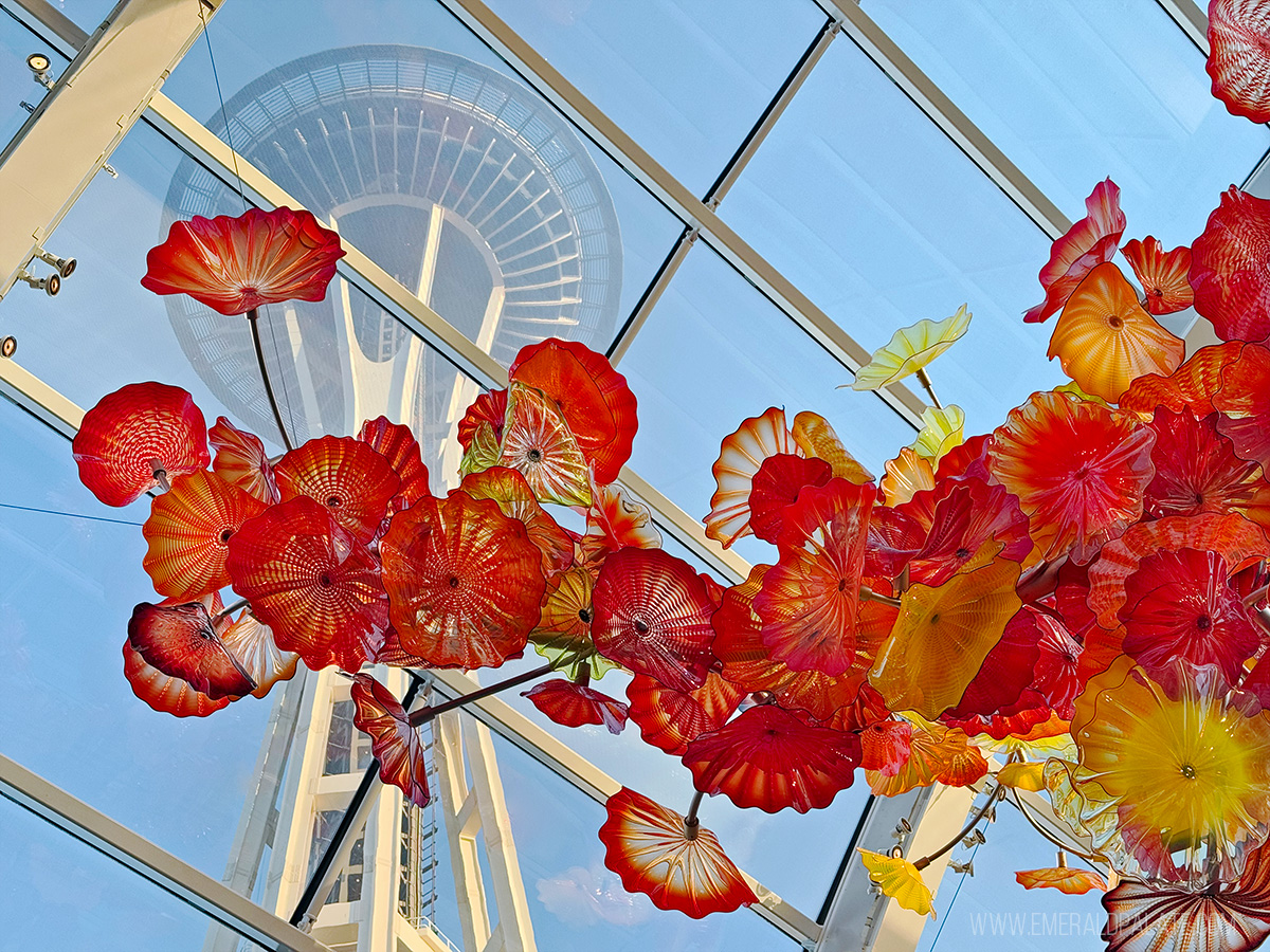 space needle viewed from below inside Chihuly Gardens and Glass Museum with an ornate glass sculpture in the foreground