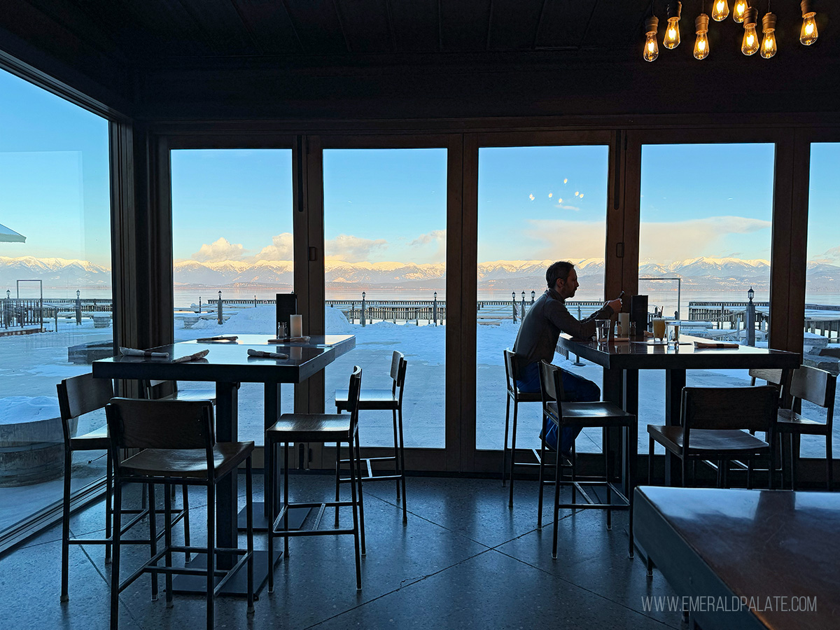 man eating at a restaurant with huge windows overlooking Flathead Lake in Montana