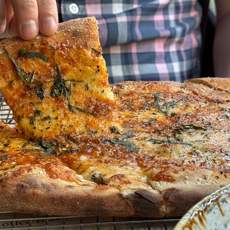 Person picking up pizza from the best pre-theater dining in Seattle