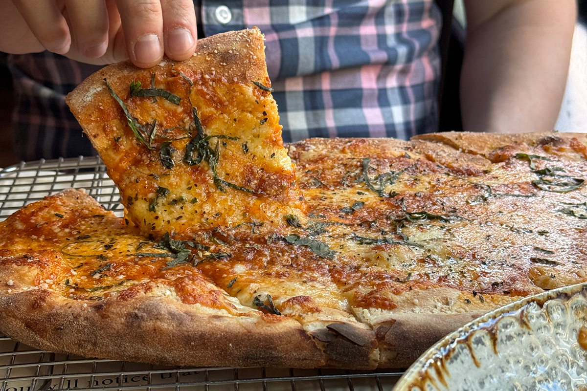 Person picking up pizza from the best pre-theater dining in Seattle