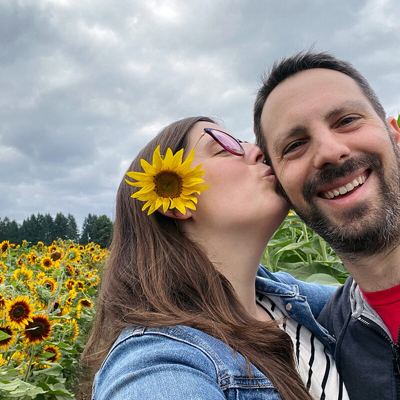 man and woman kissing in a sunflower field, one of the best anniversary ideas in Seattle