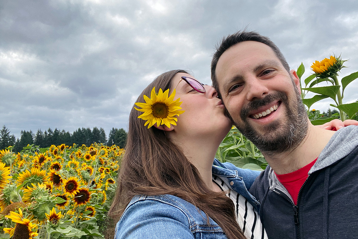 man and woman kissing in a sunflower field, one of the best anniversary ideas in Seattle